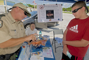 An FWC official uses a synthetic model lobster to demonstrate the proper measuring technique that divers need to employ, while in the water, in order to harvest the correct sized lobster.
